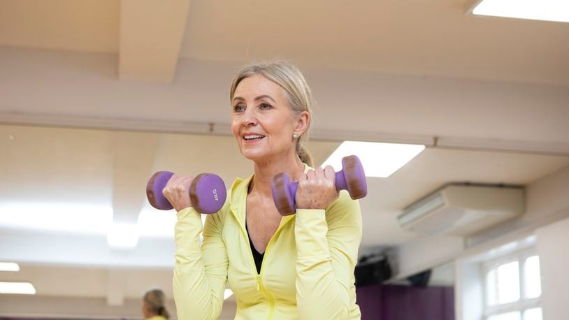 A woman is seen doing up bicep curls for strengthening her muscles.