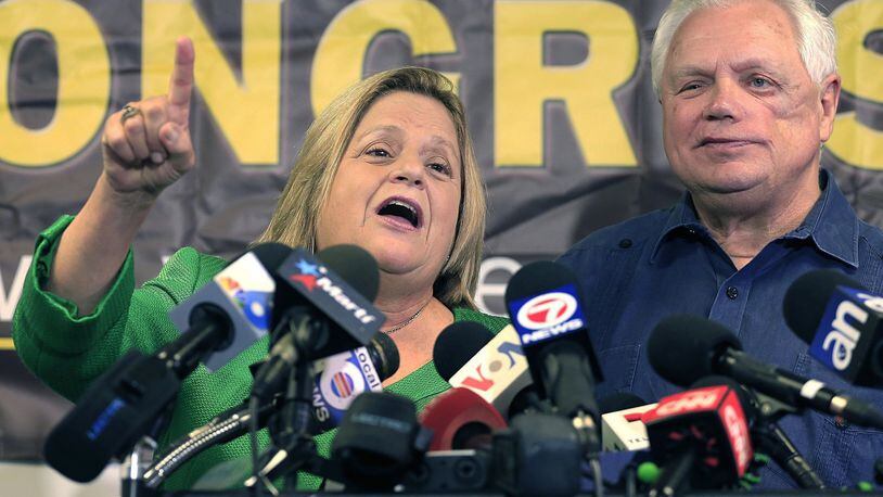 Ileana Ros-Lehtinen stands with her husband, Dexter Lehtinen, right, at the podium Monday, May 1, 2017, as she gives her final statement regarding her retirement from Congress. She says she is retiring at the end of her term next year. (Carl Juste/Miami Herald via AP)