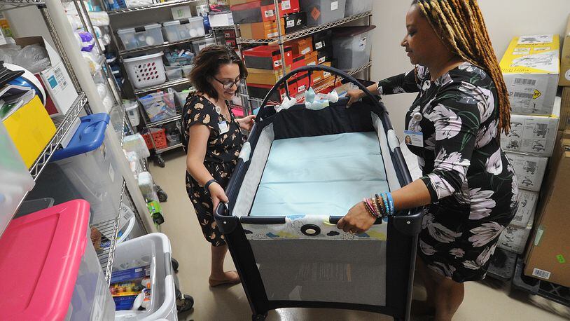 Abbey Pettiford, Injury Prevention Coordinator, left, and Maleka James, MPH, Infant & Child Wellness Initiatives, Project Manager, move a baby bed out of storage at the Connor Child Health Pavilion on Thursday, May 25, 2023. MARSHALL GORBY\STAFF