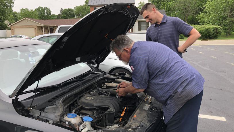Owner Taylor Sutton , in the background, consults with mechanic Terry Johnson in the parking lot of Pro Automotive in Springboro.STAFF/LAWRENCE BUDD