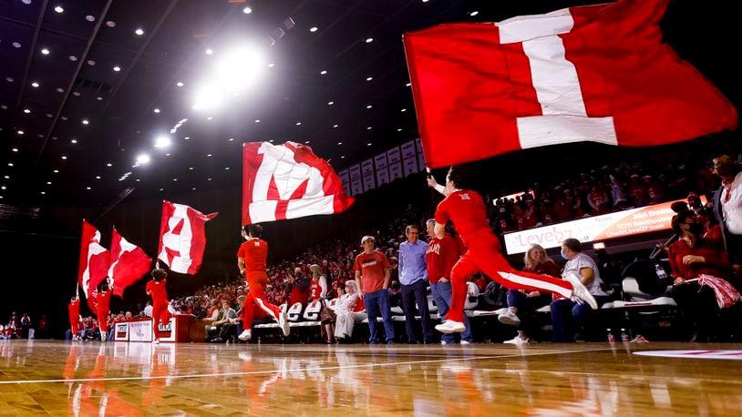 Miami University cheerleaders carry flags on the court during their basketball game against University of Cincinnati Wednesday, Dec. 1, 2021 at Millett Hall on Miami University campus in Oxford. NICK GRAHAM / STAFF