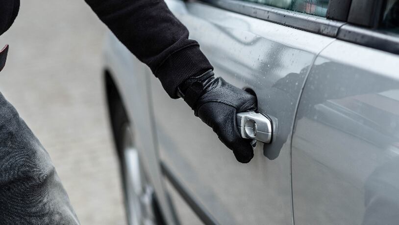 Close up on car thief hand pulling the handle of a car. Car thief, car theft concept