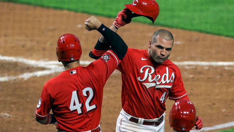 Cincinnati Reds' Eugenio Suarez, left, celebrates the two-run home run by Joey Votto, right, during the third inning of a baseball game against the Cleveland Indians in Cincinnati, Friday, April 16, 2021. (AP Photo/Aaron Doster)