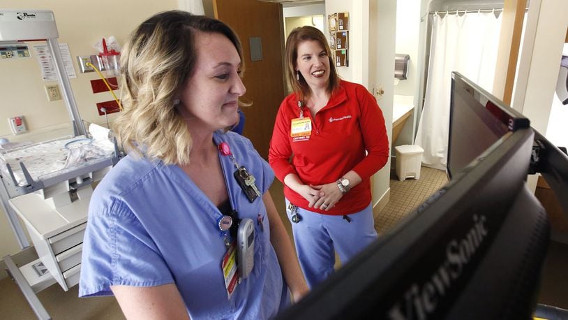 Emily Hayes, R.N., right, reviews patient records software with Adrienne Linville, R.N. at Miami Valley Hospital’s Berry Women’s Center. Demand for registered nurses is high and is reflected in the numbers of those leaving the profession. TY GREENLEES/STAFF