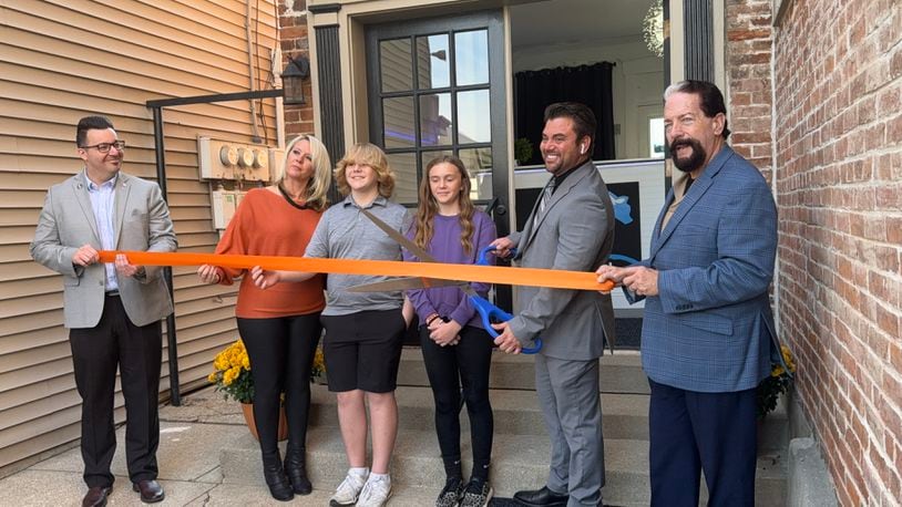Cryo Den, a cryotherapy spa, opens at 215 Main St. in Hamilton, Ohio. Pictured is the ribbon cutting with the Greater Hamilton Chamber of Commerce. Owner Jared Fox poses with the giant scissors outside the business's front door. MICHAEL D. PITMAN/STAFF
