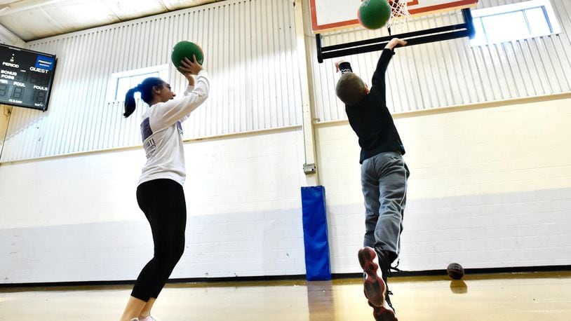 Childcare team member Mckenzie Losekamp plays basketball with a child at Lakota Family YMCA on the final day of of regular state licensed childcare Wednesday, March 25, 2020 in Liberty Twp. Lakota Family YMCA is one of 31 approved facilities with a  Temporary Pandemic Child Care  license in Butler County. Anyone who comes into the YMCA doors must have their temperature taken and parents cannot go past a table set up in the main entrance lobby. NICK GRAHAM/STAFF