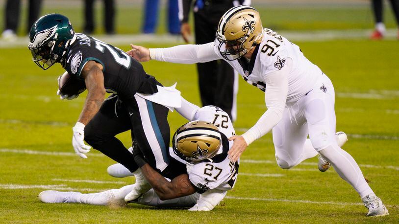 Philadelphia Eagles' Miles Sanders (26) is tackled by New Orleans Saints' Malcolm Jenkins (27) and Trey Hendrickson (91) during the first half of an NFL football game, Sunday, Dec. 13, 2020, in Philadelphia. (AP Photo/Chris Szagola)