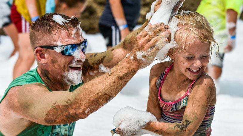 Nate Zettler and Tatum Zettler, 4, put suds on each other during the first day of the MetroParks of Butler County 12th Annual Mud Mania event Friday, Aug. 10 at Rentschler Forest MetroPark on Reigart Road in Fairfield Township. The event features mud volleyball tournaments, giant water slide, slimy obstacle course, muddy pools, vendors, and more. NICK GRAHAM/STAFF