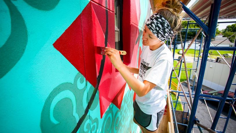 Ariel Williams works on a mural this past summer on Main Street in Hamilton. The StreetSpark program is accepting design proposals for three upcoming murals in Hamilton. GREG LYNCH/STAFF