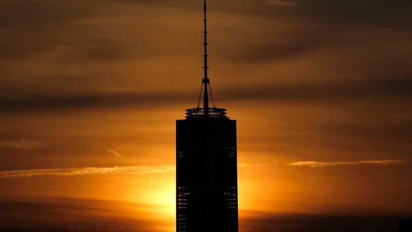 The rising sun is blocked by the One World Trade Center tower seen from The Heights neighborhood of Jersey City, N.J., Friday, Dec. 11, 2015.