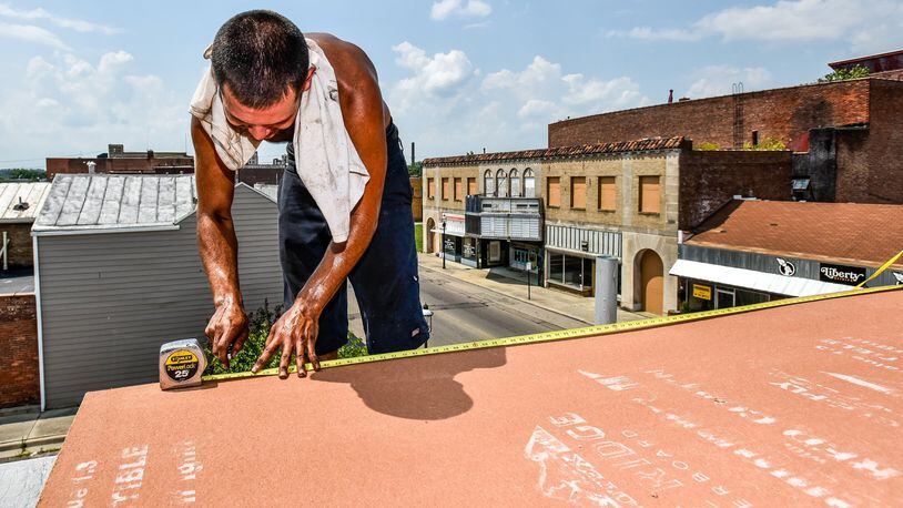 Leo Felix, with C&J Roofing, cuts underlayment while he and the crew try to stay cool as they replace rubber roofing on a building on Central Avenue Tuesday, July 18, in Middletown. NICK GRAHAM/STAFF