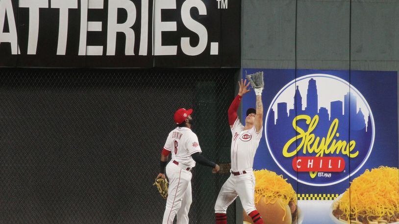 Reds center fielder Michael Lorenzen makes a catch against the wall in the ninth inning as left fielder Phillip Ervin watches during a game against the Braves on Tuesday, April 23, 2019, at Great American Ball Park in Cincinnati. David Jablonski/Staff