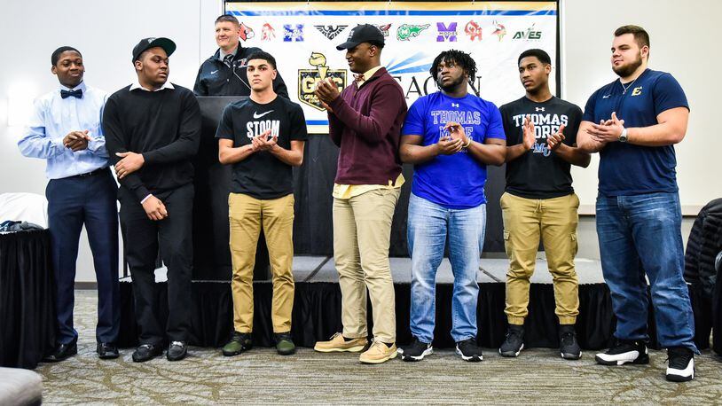 Fairfield head football coach Jason Krause (at podium) speaks about eight FHS players who have signed to play college football during the Greater Miami Conference National Signing Day event Wednesday at the Sharonville Convention Center. Left to right are Allen Caldwell (Pikeville), Mekiyell Muhammad (Lake Erie), Peyton Brown (Lake Erie), Jeff Tyus (Charleston), Greg Fitzpatrick (Thomas More), Del Thomas (Thomas More) and Jacob Hensley (East Tennessee State). Erick All (not pictured) signed early with Michigan and is already taking classes. NICK GRAHAM/STAFF