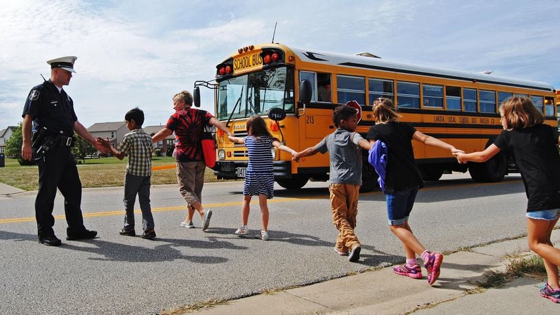 A West Chester Twp. police officer gives high-fives to Endeavor Elementary students as they board a bus to be transported to Lakota West Freshman School after a bomb threat forced the school to be evacuated in 2015. ERIC SCHWARTZBERG/STAFF