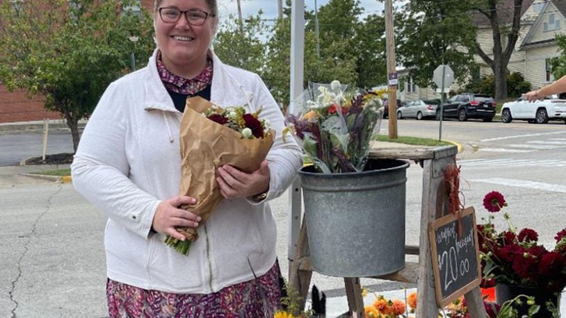 Laura Brubaker, of Little Creek Farm in West Manchester, holds a bunch of her flowers that she sells at the oxford Farmers Market. XINGRUI LU/OXFORD OBSERVER