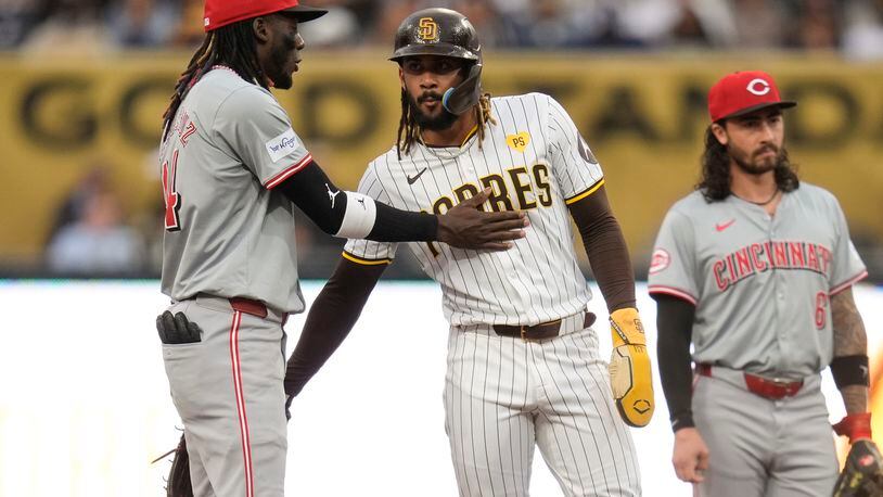 San Diego Padres' Fernando Tatis Jr., center, talks with Cincinnati Reds shortstop Elly De La Cruz, left, as he stands on second base after advancing from first off a fielder's choice by Jake Cronenworth during the first inning of a baseball game, Tuesday, April 30, 2024, in San Diego. (AP Photo/Gregory Bull)