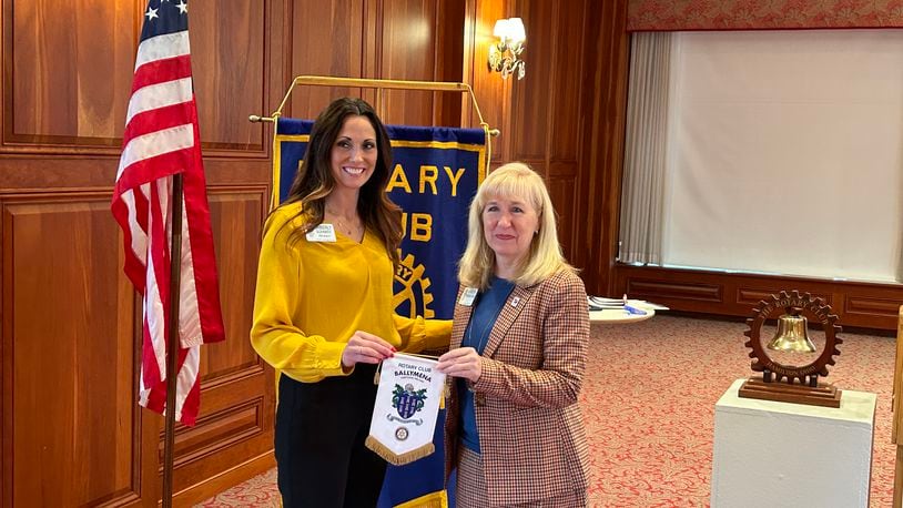 Kim Schmidt, left, president of the Hamilton Rotary Club, accepts a banner from the Ballymena, Northern Ireland Rotary Club from Karen Underwood Kramer, who visited there last month. RICK McCRABB/STAFF