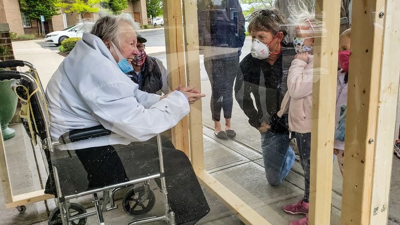 The family of Virginia “Ginny” Meyer, 95, was finally able to see her up closed thanks to a clear, protective box the family built to be placed outside Barrington of West Chester senior living facility Wednesday, May 13, 2020. Meyer’s children, grandchildren and great-grandchildren greeted her as she came out the door to see them up close for the first time in over two months due to the coronavirus pandemic. If they wanted to see her before they had to see her from her third floor balcony. NICK GRAHAM / STAFF