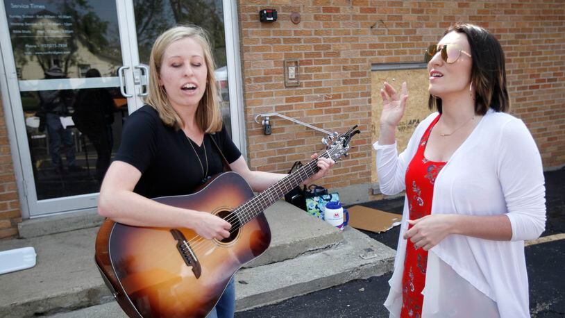 Jordan Wilson, left, and Amanda Whelden played and sang worship songs at Northridge Wesleyan Church where Pastor C. Scott Ritz held a Sunday service in the parking lot of the tornado damaged church in Harrison Twp. Ritz said the church has insurance to take care of their building but his main concern is helping the community.     TY GREENLEES / STAFF