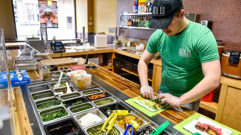 Zach Scheyer prepares a lunch entree Friday, April 5, 2019, at Roll On In Sushi Burritos & Bowls at 102 Main St. in Hamilton. The fast casual chain opened a new location July 14 in Warren County’s Hamilton Twp. and plans to introduce a Buzzed Bull Creamery into both locations later this year. NICK GRAHAM/STAFF