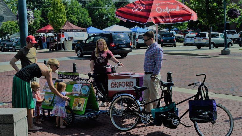Chuck and Lori Rey with their children, Tripp and Siena, look over the book selection on the Oxford Lane Public Library’s Bike-Mobile. Looking on is Bethany MacMillan with Enjoy Oxford’s Ambassador Bike, along with Chad Wonsik, of the Lane Library. The two bikes are Uptown on Saturday mornings. CONTRIBUTED/BOB RATTERMAN