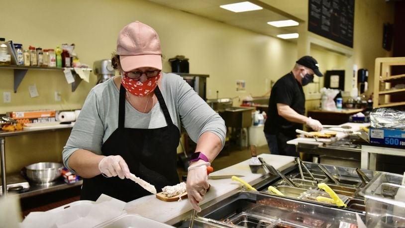 Les Rudisell and wife Debbie prepare food on their first day open in six weeks at Alexander s Market and deli on High Street in Hamilton Tuesday, May 5, 2020. NICK GRAHAM / STAFF
