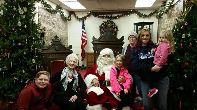 Santa Claus sits next to Ann Dennett, longtime chairwoman of the German Village Christmas Walk. They are pictured with Dennett’s daughter Debbie, and Dennett’s four great grandchildren, Kylie, Lucas, Charlotte and Clara. CONTRIBUTED