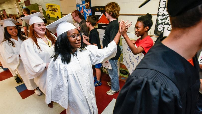 Lakota East senior Abena Acheampong gives a high five to Hopewell elementary sixth-grader Tafara Gwangwava as the soon-to-be graduating seniors marched through the hallway of Hopewell Elementary to the applause and cheers of the elementary students Monday, May 15. NICK GRAHAM/STAFF
