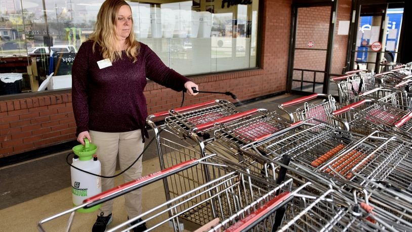 Lauren Schuerman, a manager at Needler s Fresh Market, on N. University Blvd. in Middletown sprays sanitizer in carts at the entrance Tuesday morning. A sign on the door says a maximum of 117 customers are allowed in the store at a time. (Photo By Nick Graham/Journal-News)
