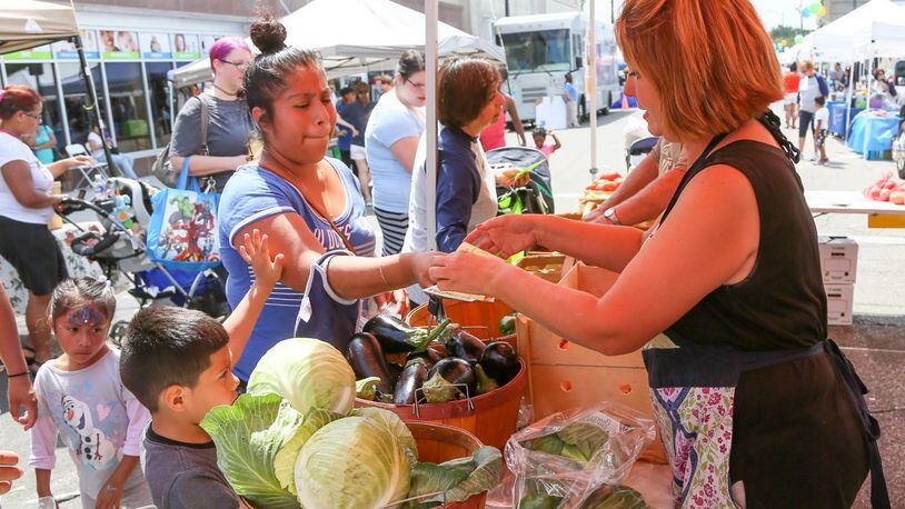 Butler County WIC and Primary Health Solutions hosted a block party on Second Street, Tuesday, Aug. 15, 2017, to celebrate WIC’s Farmers Market Nutrition Program. Suzanne Garver of Garver Family Farms helps customers pick out produce during the event. GREG LYNCH / STAFF
