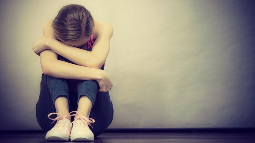 Sad depressed young teenage girl sitting by wall hiding face. School, adolescence, home violence, unwanted love problems. (Voyagerix/Getty Images/iStockphoto)