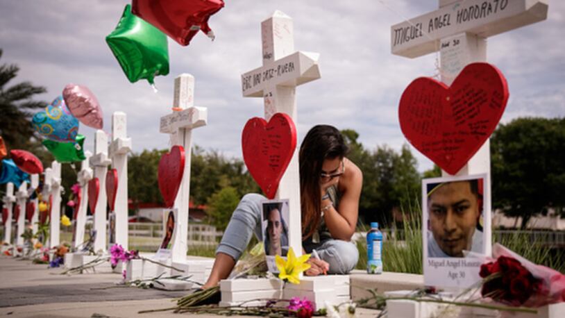 ORLANDO, FL - JUNE 17: A woman writes a note on a cross for Eric Ivan Ortiz-Rivera at a memorial with wooden crosses for each of the 49 victims of the Pulse Nightclub, next to the Orlando Regional Medical Center, June 17, 2016 in Orlando, Florida. The shooting at Pulse Nightclub, which killed 49 people and injured 53, is the worst mass-shooting event in American history. (Photo by Drew Angerer/Getty Images)
