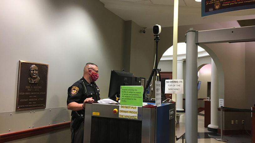 Butler County Sheriff’s Deputy Melvin Noes stands at the monitor at the security check point at the court wing of county common pleas court Tuesday. A new thermal imaging camera that takes the temperature of everyone who passes in front of it sits on top of the X-ray machine. LAUREN PACK/STAFF