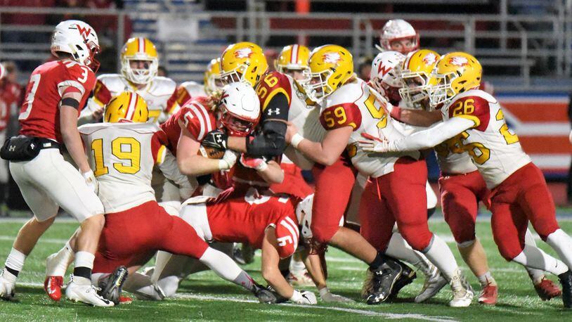 It took a lot of Fenwick players to bring Wapakoneta fullback Evan Kaeck (5) down Friday night during a Division III, Region 12 playoff semifinal at Piqua’s Purk Field at Alexander Stadium. Falcons on this play included Tyler Houck (19), Leo Bell (59), Logan Miller (26), John Stevenson (38) and Sam Secrest (56). CONTRIBUTED PHOTO BY ANGIE MOHRHAUS