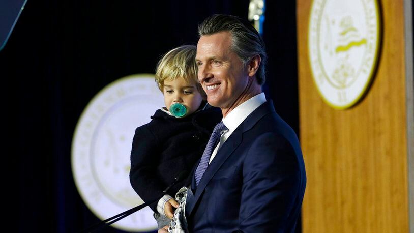 California Governor Gavin Newsom holds his son, Dutch, while speaking during his inauguration Monday, Jan. 7, 2019, in Sacramento, California.