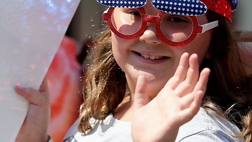 A young girl waves to spectators as she participates in the 4th of July parade in Hamilton Tuesday, July 4, 2017.