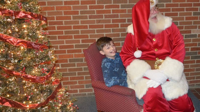 Santa Claus turned the tables on one young man during their visit Dec. 1 at the Holiday Festival by sitting on his lap, drawing laughs from all in the area. Santa provided many memories for kids and parents during the evening. CONTRIBUTED/BOB RATTERMAN