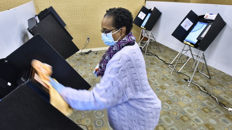 Butler County Board of Elections volunteer Jillynn Whitlow cleans voting machines on the first day of early voting Tuesday, October 6, 2020 in Hamilton. NICK GRAHAM / STAFF
