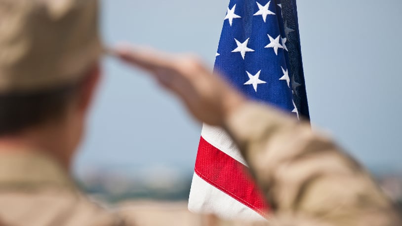 Soldier salutes flag (stock photo).