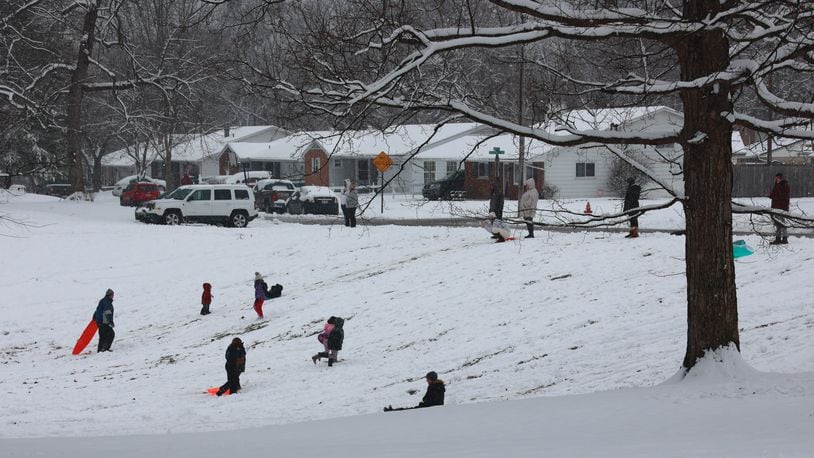 Families sled down a hill at Smith Park in New Carlisle Sunday. BILL LACKEY/STAFF
