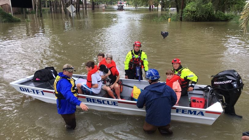 Members of Ohio Task Force 1 evacuates people from an apartment complex who were trapped by rising waters in the Houston area on Tuesday. Many of the Kettering-based task force s members are from southwest Ohio. CHUCK HAMLIN/STAFF