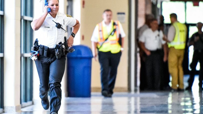 Hamilton police officer Amanda Cox runs down the hallway of Hamilton High School during a training drill with Hamilton City School District in June.