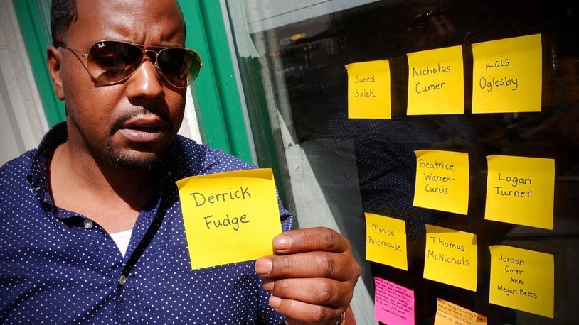 Dion Green’s father Derrick Fudge was one of the victim’s of the Oregon Street shooting two years ago holds up a post-it note with his father’s name that someone had left with the other names for victims on a window on Fifth St., Tuesday, August 2, 2021. MARSHALL GORBY\STAFF