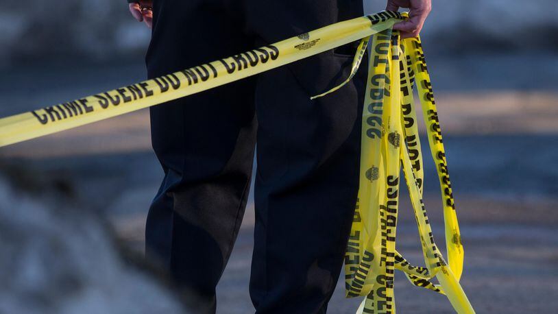 A police officer pulls crime scene tape across a crime scene in this file photo.