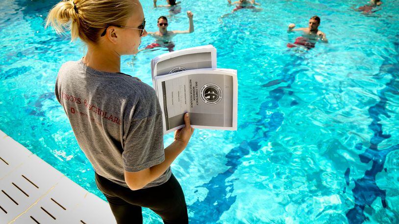 Head Lifeguard Morgan Avers holds pages of a checklist as she monitors lifeguards treading water as they are being trained at the Miamisburg pool in preparation for the summer swimming season in 2015. JIM WITMER/STAFF