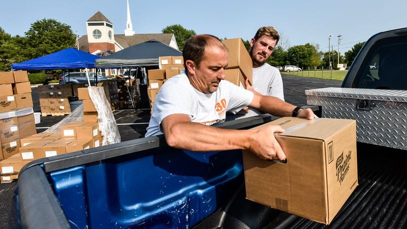 Clint Miracle, left, and Joshua Smalley, volunteers at Lakota Hills Baptist Church on Tylersville Road in West Chester Township, load up boxes of food for the Farmers to Families food program Tuesday, Sept. 15, 2020. NICK GRAHAM / STAFF