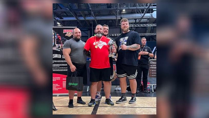 Surrounded by international strongmen stars, Middletown's Mike Diehl (center) accepts the second-place trophy last weekend in Great Britain. It was Diehl's fourth, disabled strongman international medal finish in the last year. (Provided Photo\Journal-News)