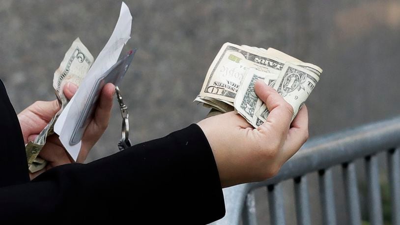 A woman pays with cash as she buys from a street vendor, Sept. 26, 2017 in New York. Despite numbers showing a healthy economy overall, lower-income spenders are showing the strain. (AP Photo/Mark Lennihan)