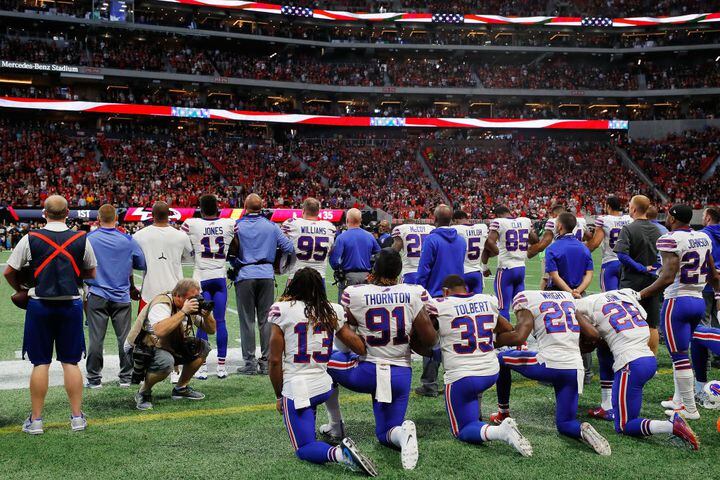 nfl players stand, kneel and raise fists