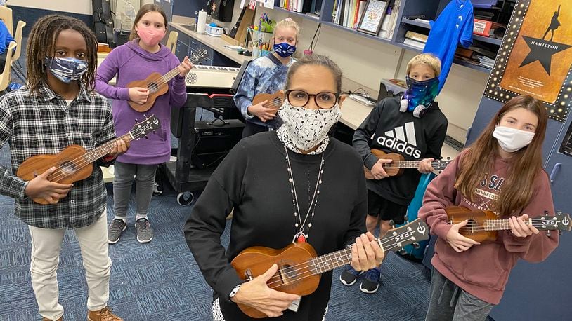 Larissa McIntosh (center), sixth grade choir and strings teacher at Springboro Intermediate School, organized a fundraiser to purchase ukuleles for her choir students to learn and play. CONTRIBUTED PHOTO / SCOTT MARSHALL
